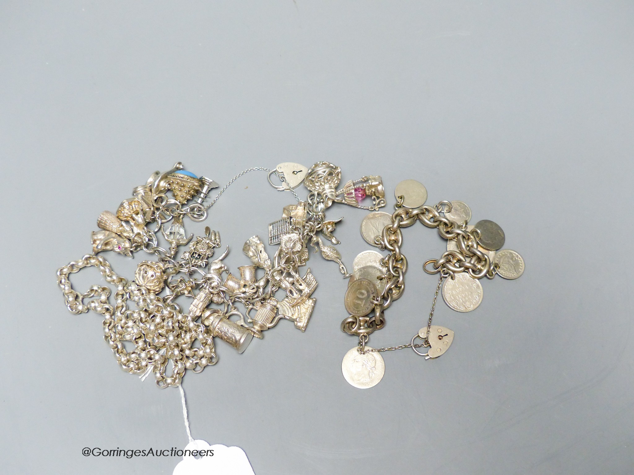 A silver charm bracelet, a silver necklace and a silver silver bracelet mounted with various coins, gross 224 grams.